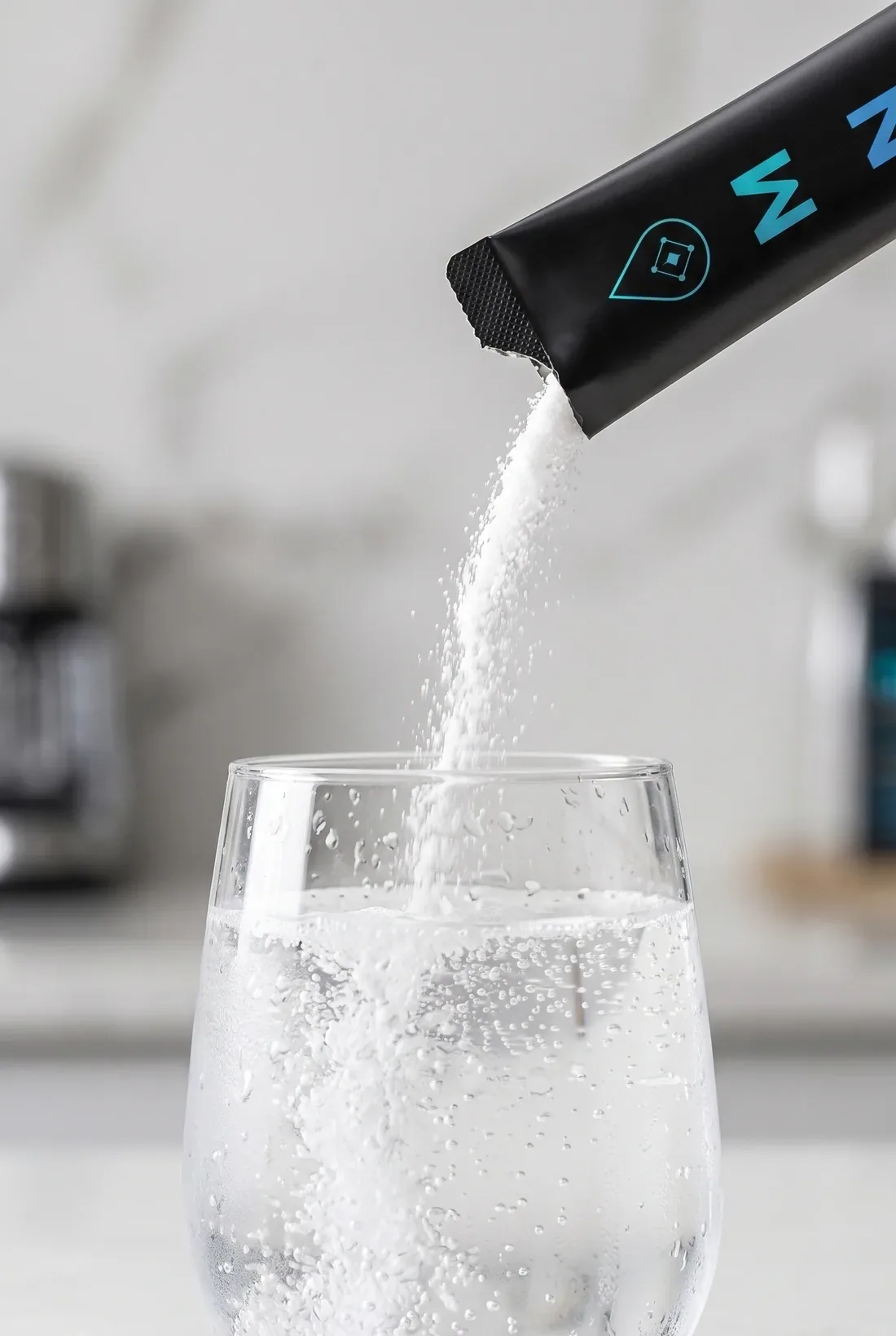 A black MNRL stick pack pouring powder into a glass of water